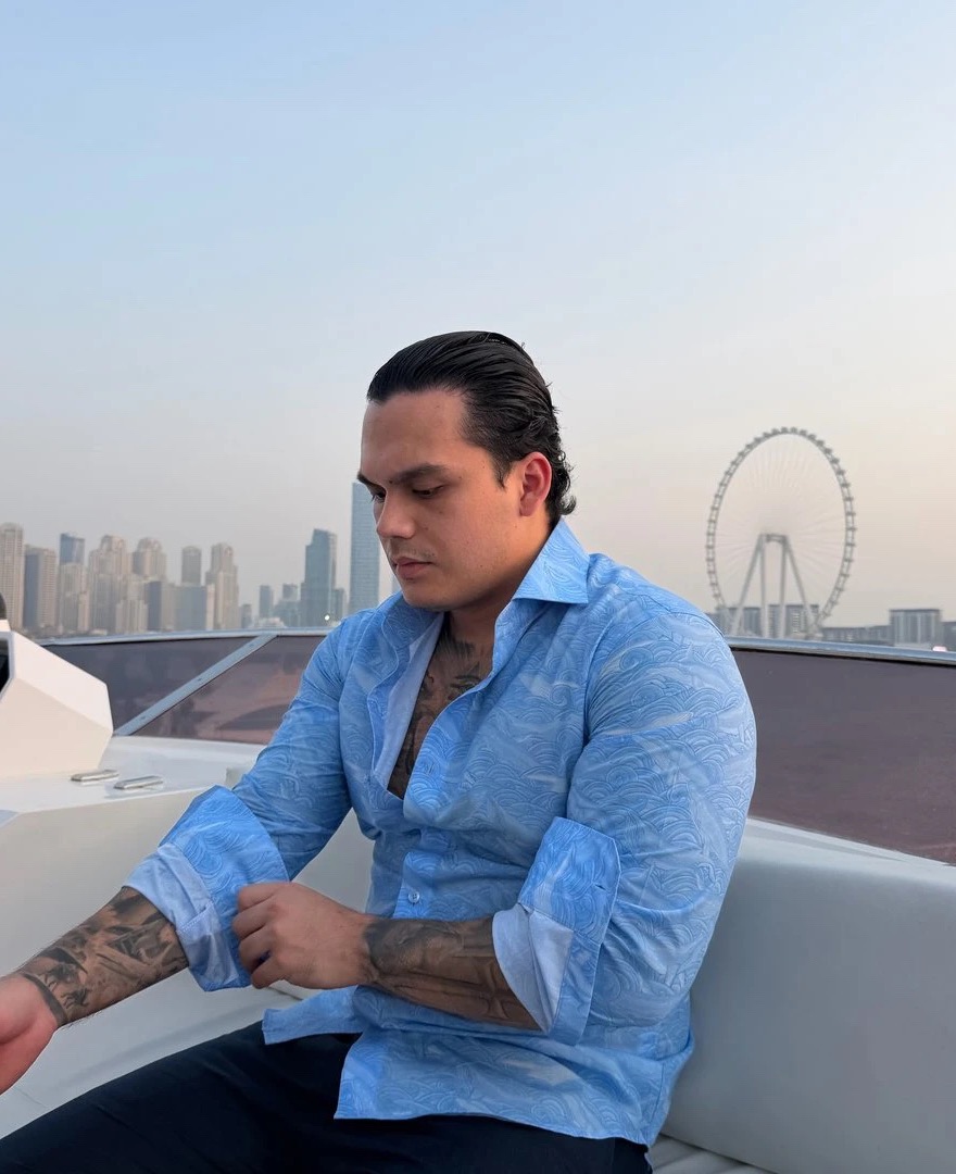 Juan Martínez en un yate en Dubái, con camisa azul, al atardecer